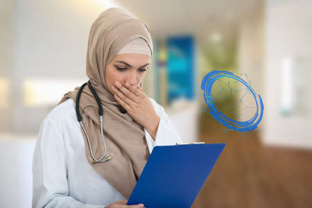 portrait of worried muslim female Medical doctor holding paperclip.の写真素材