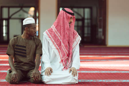 Two religious muslim man praying together inside the mosque.の写真素材