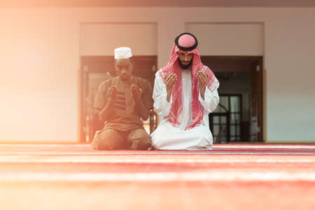 Two religious muslim man praying together inside the mosque.の写真素材