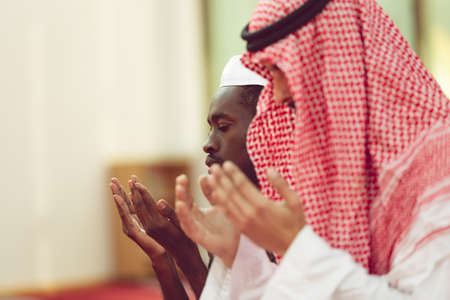Two religious muslim man praying together inside the mosque.の写真素材