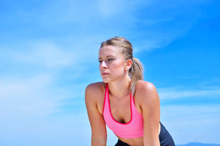 Sweaty fitness woman tired after training. Caucasian female athlete sweating and exhausted after exercising on sky copy space background.の写真素材