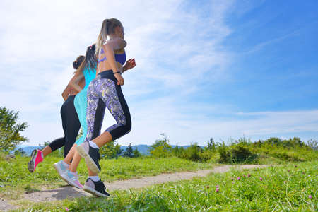 Three Female Joggers running together on trail outdoors.の写真素材
