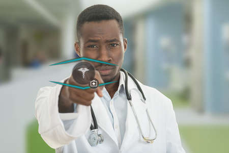 Angry african black male doctor pointing finger at you with stethoscope around his neck, pointing at camera with serious face and medical symbols.の写真素材