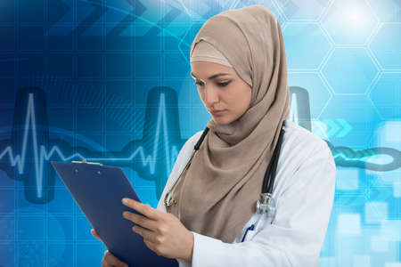 Closeup portrait of friendly, smiling confident muslim female doctor holding folder, healthcare professional.の写真素材