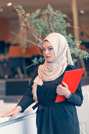 Arabian business woman holding a folder in modern startup officeの写真素材