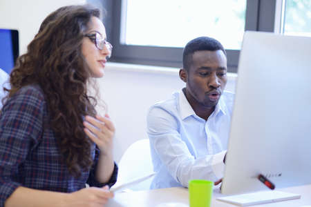 Group of entrepreneurs working using a laptop and holding a document