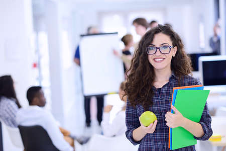 business, startup and people concept - happy creative team with computer and folder in office