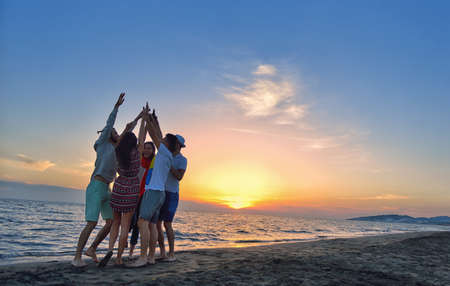 group of happy young people dancing at the beach on beautiful summer sunsetの写真素材