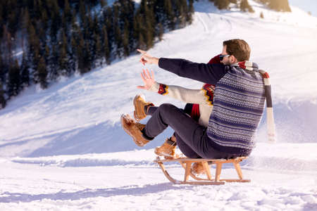 Young Couple Sledding And Enjoying On Sunny Winter Dayの写真素材