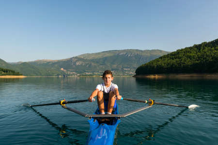 The young sportsman is rowing on the racing kayak