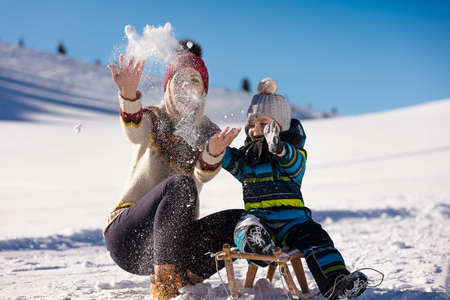 parenthood, fashion, season and people concept - happy family with child on sled walking in winter outdoorsの写真素材