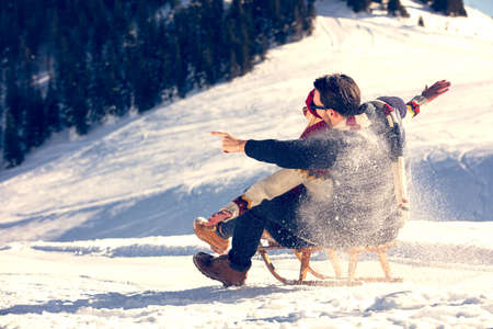 Young Couple Sledding And Enjoying On Sunny Winter Dayの写真素材