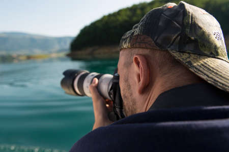 Photographer in nature taking pictures to a beautiful lakeの写真素材