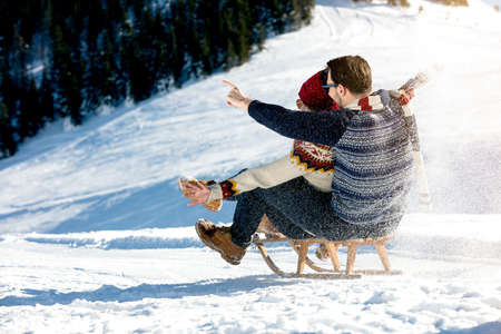 Young Couple Sledding And Enjoying On Sunny Winter Dayの写真素材
