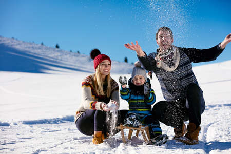 parenthood, fashion, season and people concept - happy family with child on sled walking in winter outdoorsの写真素材