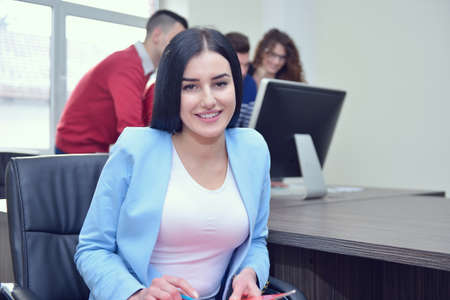 Beautiful girl sitting in office in front of desktopの写真素材