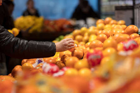 females hand pick up Sunkist orange in market.の写真素材