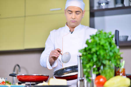 cook chef in kitchen and fresh vegetables on table