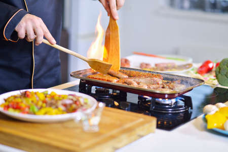 mature chef preparing a meal with various vegetables and meatの写真素材