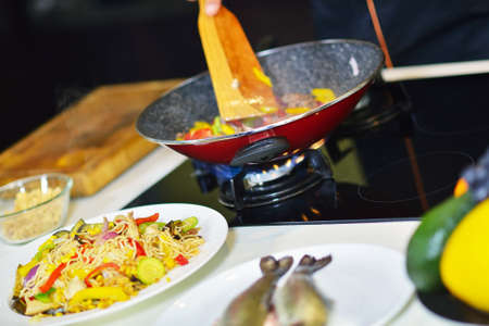 Vegetable ragout in pan, on wooden table on bright background