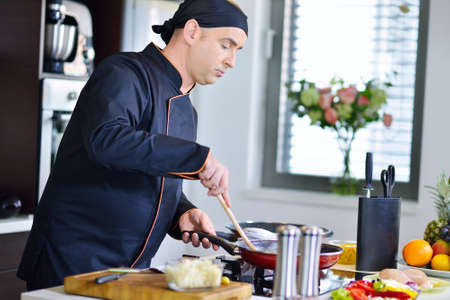 mature chef preparing a meal with various vegetables and meat