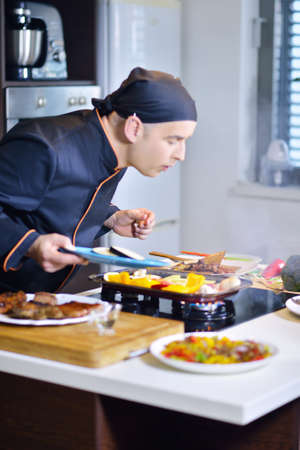 mature chef preparing a meal with various vegetables and meatの写真素材