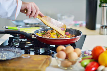 mature chef preparing a meal with various vegetables and meatの写真素材