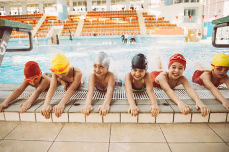 happy children kids group at swimming pool class learning to swim