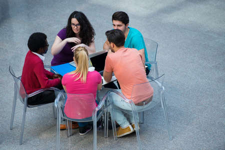 Multiracial group of young students studying together. High angle shot of young people sitting at the table.の写真素材