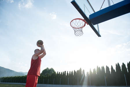 Young man jumping and making a fantastic slam dunk playing streeの写真素材