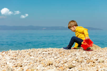 cute baby boy playing on the beach with waterの写真素材