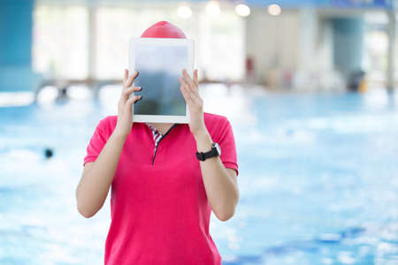 Fit female swimming trainer with tablet at the poolの写真素材