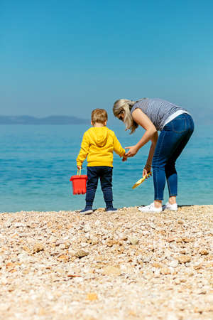 A happy mother and young child boy son having fun on a sunny beach