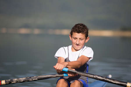 A Young single scull rowing competitor paddles on the tranquil lakeの写真素材