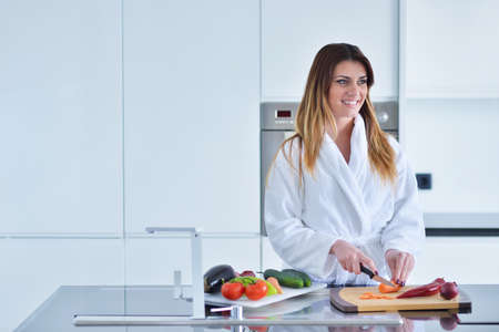 Smiling beautiful woman preparing salad at morning breakfast. Photo of young woman in bathrobe. Diet. Healthy lifestyleの写真素材