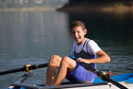 A Young single scull rowing competitor paddles on the tranquil lakeの写真素材