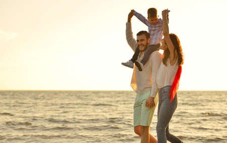 happy young family have fun on beach run and jump at sunsetの写真素材