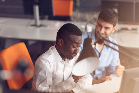 Image of two young businessmen interacting at meeting in officeの写真素材