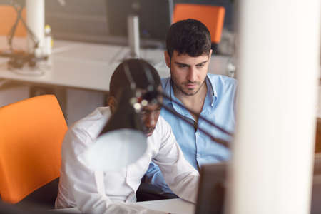 Image of two young businessmen interacting at meeting in officeの写真素材