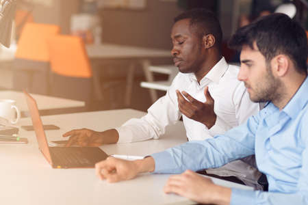 Image of two young businessmen interacting at meeting in office.