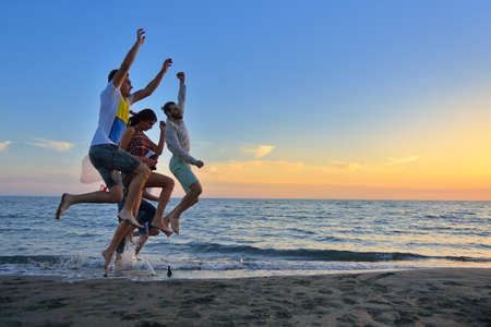 Group of happy young people is running on background of sunset beach and seaの写真素材