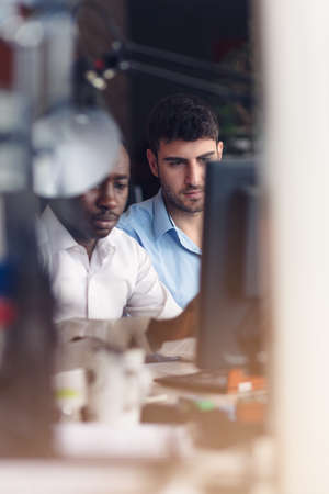 Image of two young businessmen interacting at meeting in officeの写真素材
