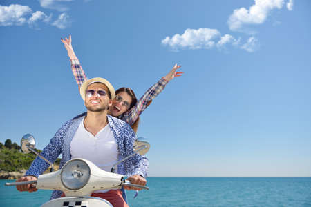 Beautiful young couple in love enjoying and having fun riding on a scooter in a beautiful nature