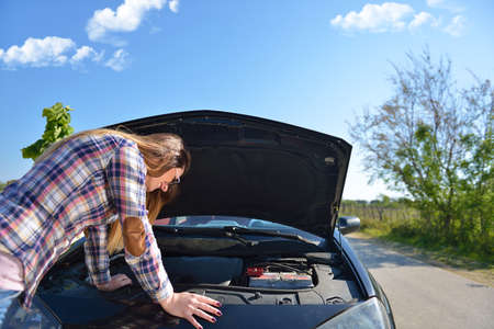 Women spection She opened the hood Broken car on the side See engines that are damaged or not.
