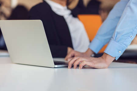 Colleagues chatting, sitting together at office table, smilingの写真素材