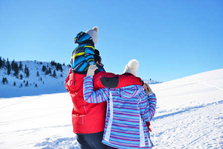 happy young family playing in fresh snow at beautiful sunny winter day outdoor in natureの写真素材