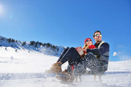 Young Couple Sledding And Enjoying On Sunny Winter Dayの写真素材