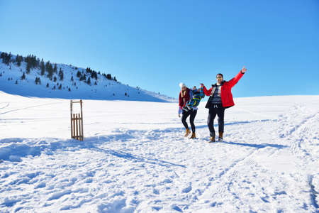 happy young family playing in fresh snow at beautiful sunny winter day outdoor in natureの写真素材