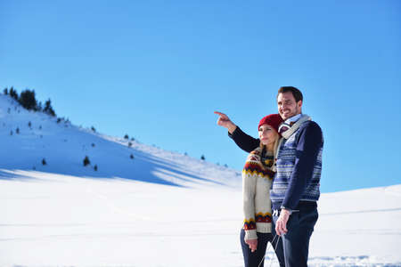 Loving couple embracing in winter park. They put colored caps and scarves.