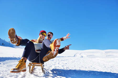 Young Couple Sledding And Enjoying On Sunny Winter Day